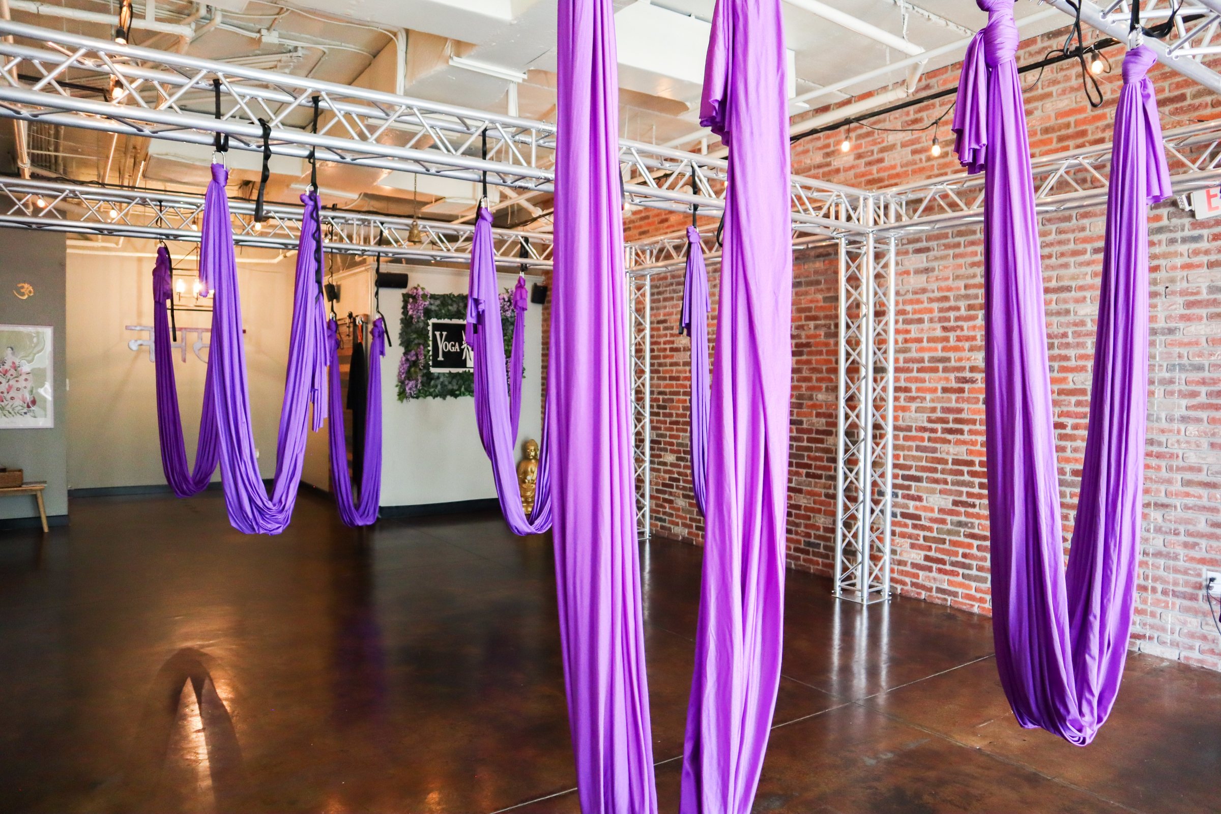 Yoga Loft Tampa aerial studio — purple hammocks, exposed brick, namaste wall in Historic Ybor City